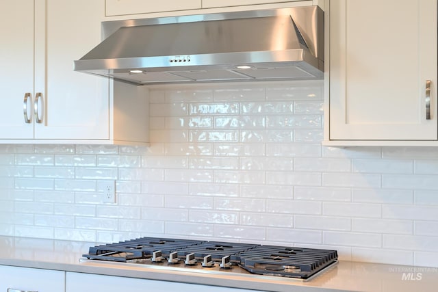 kitchen with decorative backsplash, white cabinetry, stainless steel gas cooktop, and range hood