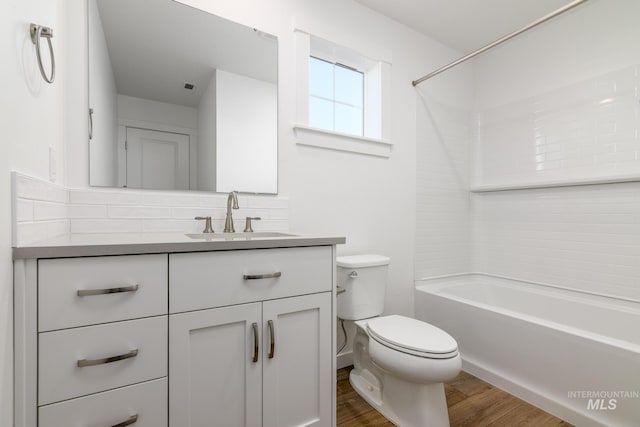 full bathroom with washtub / shower combination, wood-type flooring, toilet, decorative backsplash, and vanity