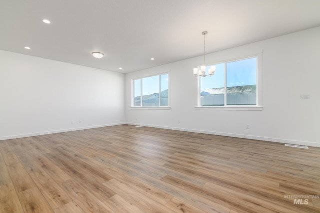 empty room with light wood-type flooring and a chandelier