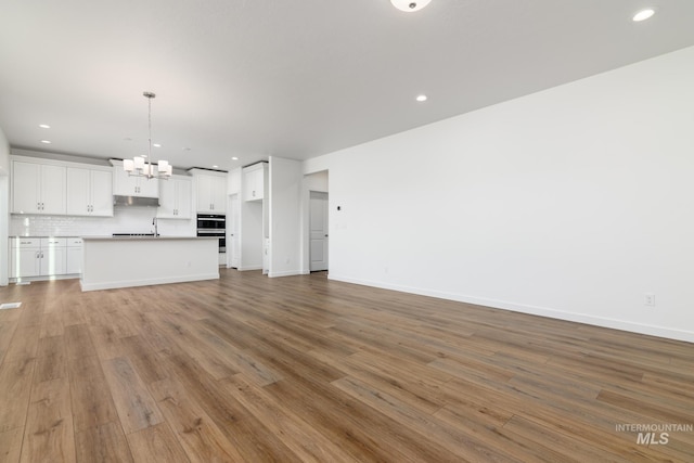 unfurnished living room featuring light wood-type flooring and a chandelier