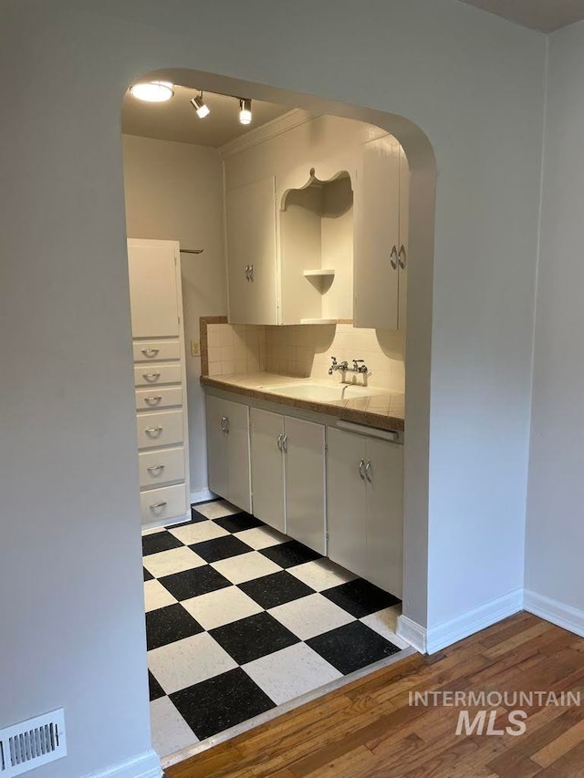 kitchen featuring dark wood-type flooring, white cabinetry, sink, and decorative backsplash