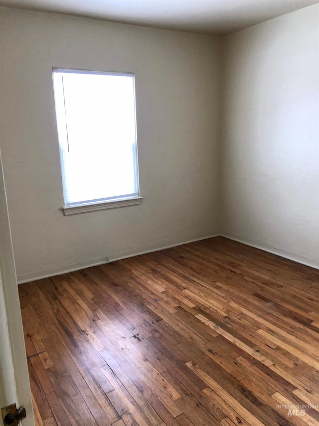 unfurnished room with dark wood-type flooring