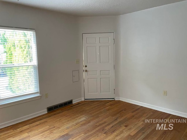 unfurnished room featuring a textured ceiling and hardwood / wood-style flooring