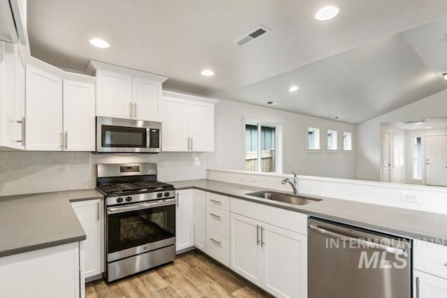 1116 N Peakhurt Ave, Kuna, ID 83634 - kitchen with appliances with stainless steel finishes, a peninsula, light wood-type flooring, white cabinetry, and backsplash