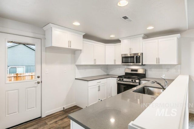 1116 N Peakhurt Ave, Kuna, ID 83634 - kitchen featuring stainless steel appliances, tasteful backsplash, dark wood-style floors, white cabinets, and recessed lighting