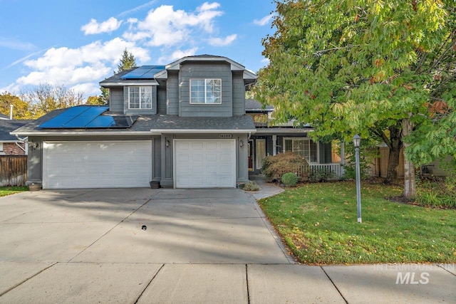 view of property with a garage, solar panels, and a front lawn