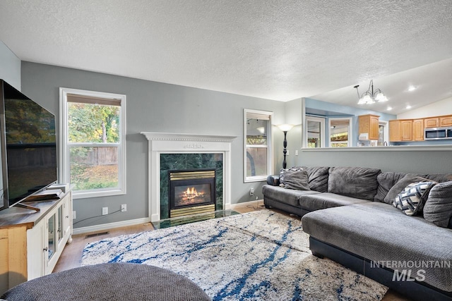 living room featuring a fireplace, a textured ceiling, light hardwood / wood-style flooring, and lofted ceiling