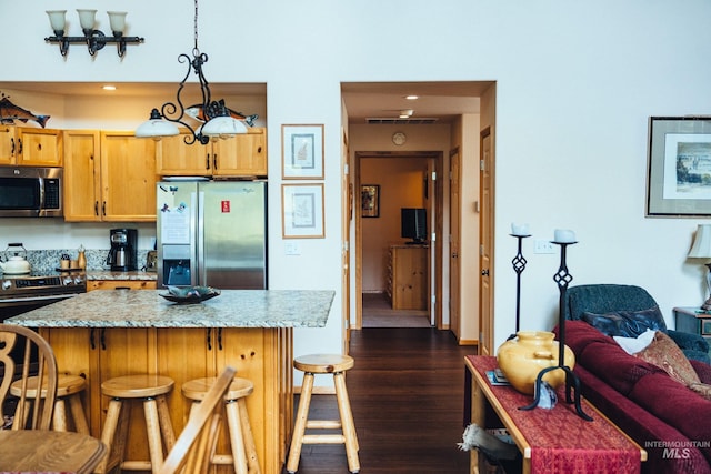 1013 Penstemen Pl, Mccall, ID 83638 - kitchen with appliances with stainless steel finishes, a breakfast bar area, dark wood finished floors, decorative light fixtures, and a kitchen island