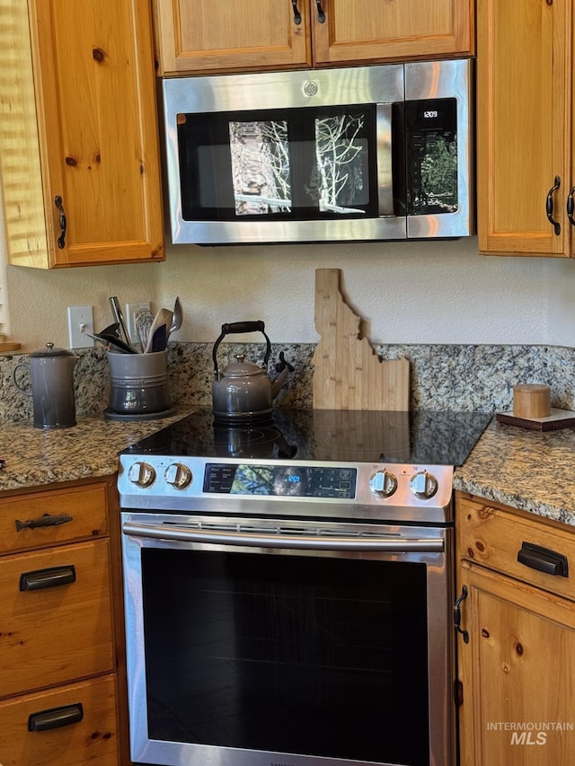 1013 Penstemen Pl, Mccall, ID 83638 - kitchen featuring appliances with stainless steel finishes, brown cabinetry, and stone countertops