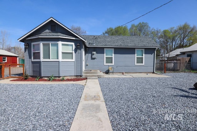 view of front of property with roof with shingles and fence