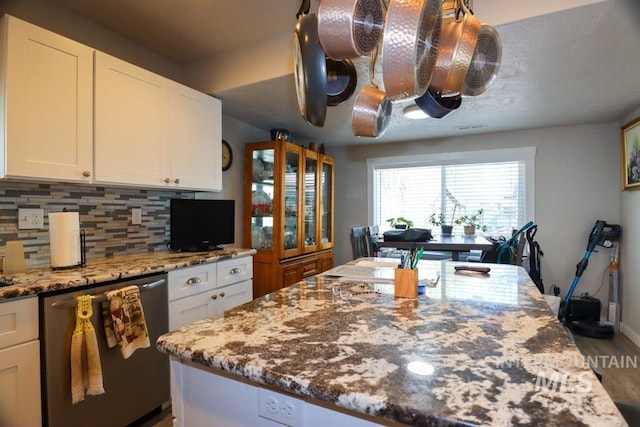 kitchen with white cabinets, light stone countertops, dishwasher, and backsplash