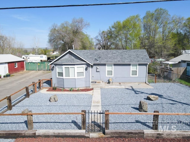 ranch-style house with roof with shingles, a gate, and a fenced front yard