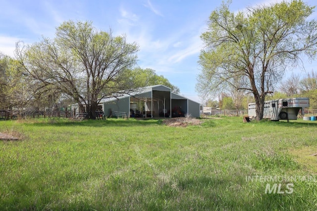 view of yard with a carport, fence, and an outbuilding