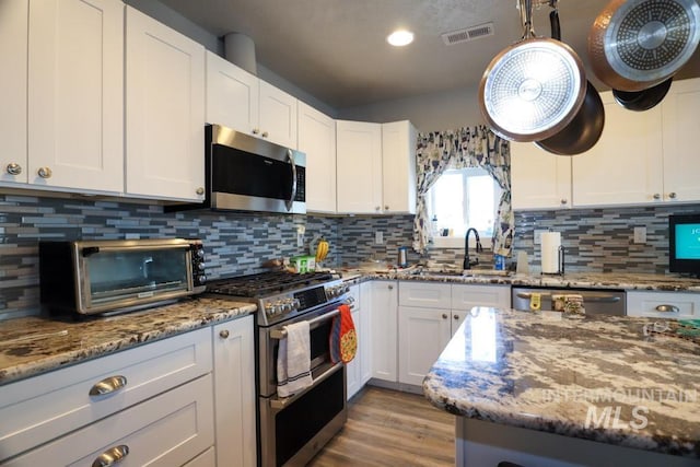 kitchen with visible vents, a sink, stainless steel appliances, decorative backsplash, and a toaster