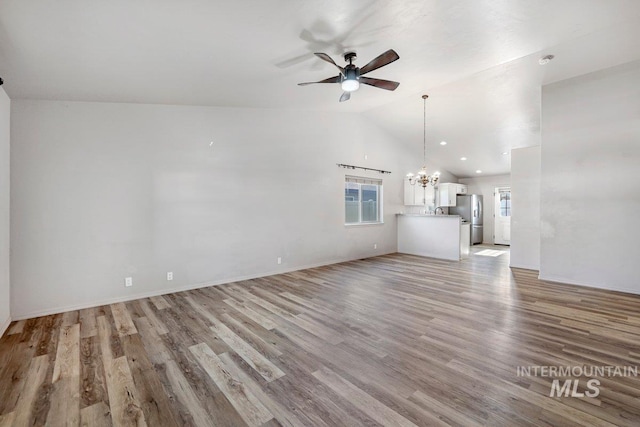 1022 S Date St, Jerome, ID 83338 - unfurnished living room featuring a chandelier, ceiling fan, vaulted ceiling, and light wood finished floors