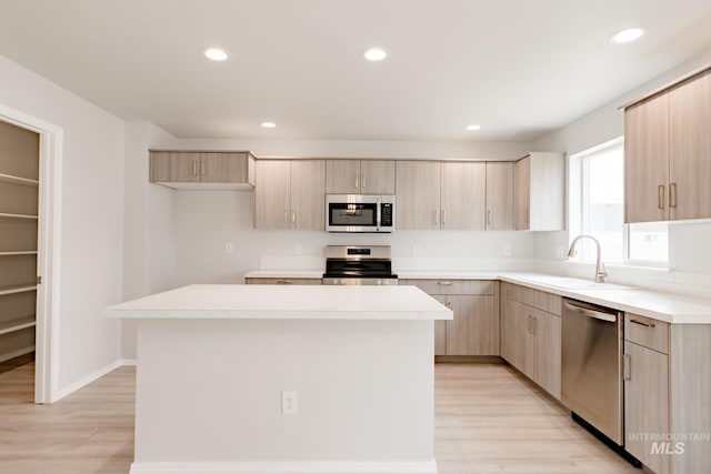 kitchen featuring a kitchen island, appliances with stainless steel finishes, sink, and light brown cabinetry