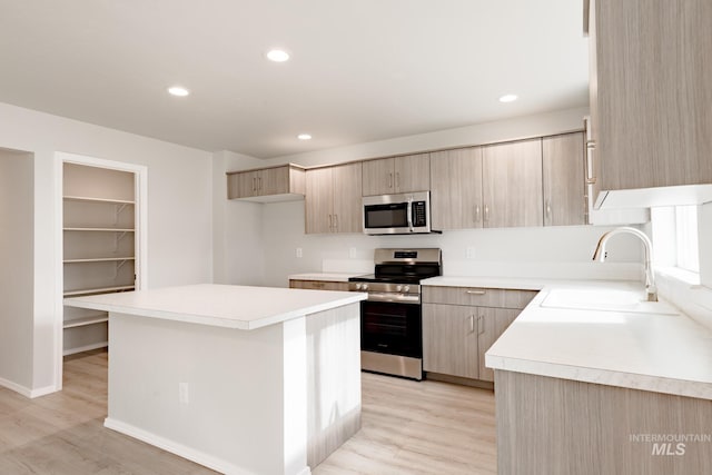 kitchen featuring sink, light hardwood / wood-style flooring, appliances with stainless steel finishes, a center island, and light brown cabinetry