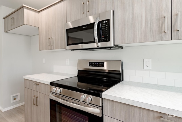 kitchen with stainless steel appliances, light brown cabinets, and light wood-type flooring