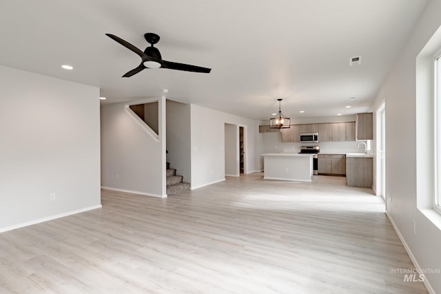 unfurnished living room featuring ceiling fan, sink, and light hardwood / wood-style flooring