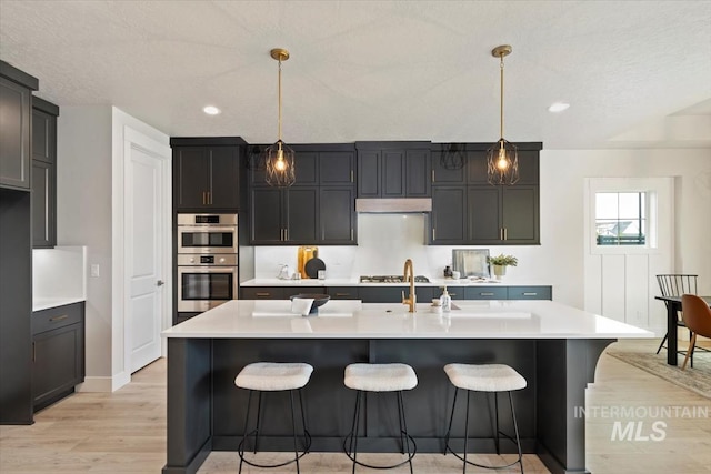 7680 W Old School St, Meridian, ID 83646 - kitchen with light wood-style flooring, light countertops, a breakfast bar, stainless steel double oven, and recessed lighting