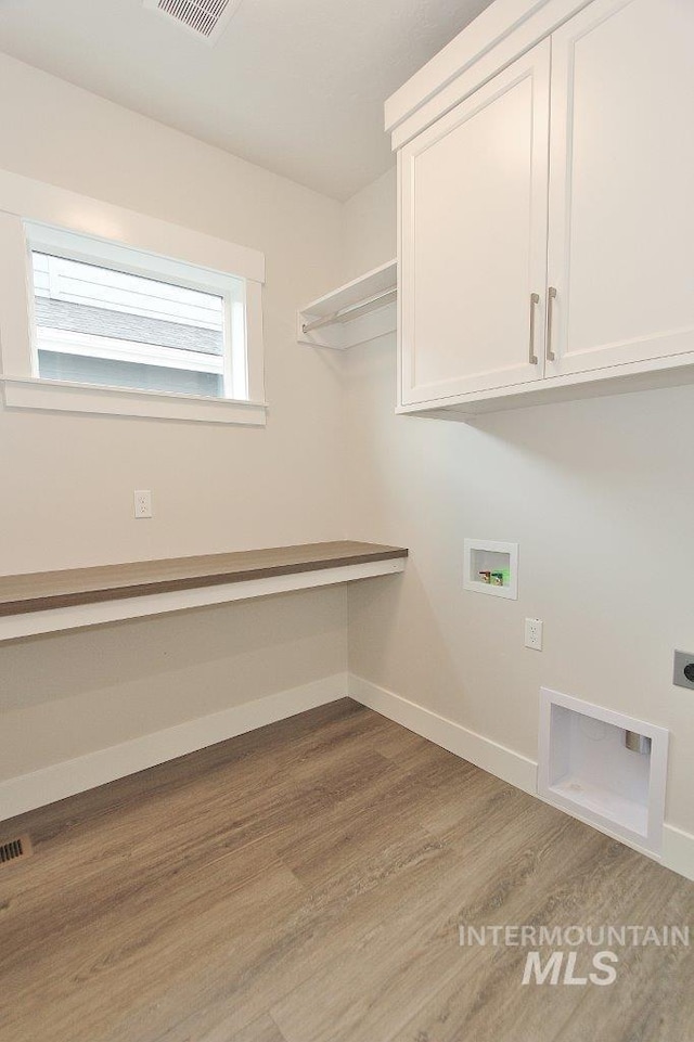 washroom featuring hookup for a washing machine, wood finished floors, baseboards, cabinet space, and electric dryer hookup