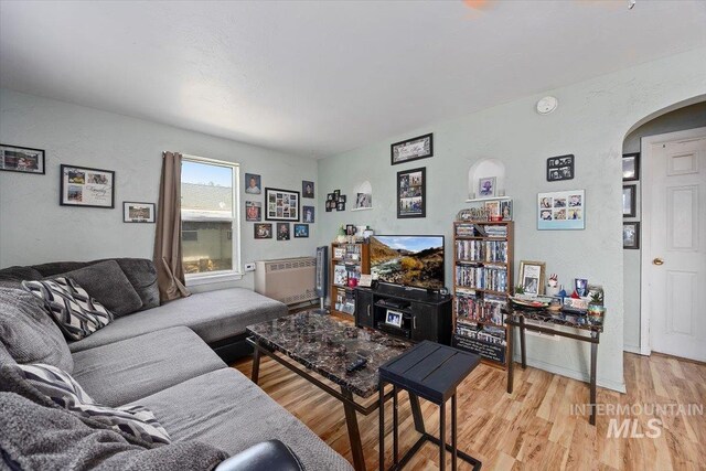 722 Nevada St, Gooding, ID 83330 - living area with arched walkways, light wood-style floors, and radiator heating unit