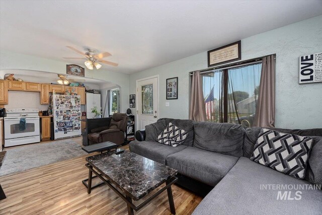 722 Nevada St, Gooding, ID 83330 - living room with arched walkways, light wood-style flooring, a ceiling fan, and a textured wall