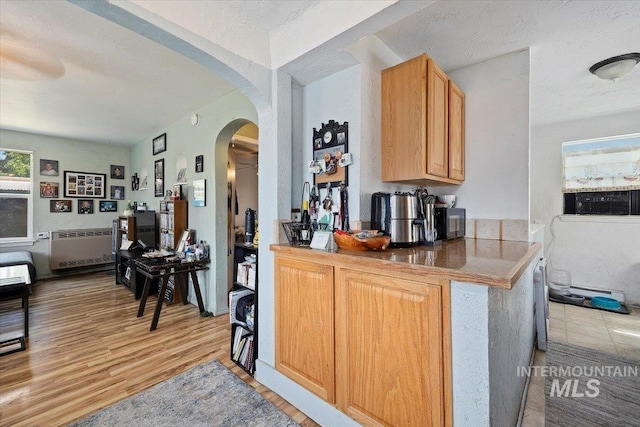 722 Nevada St, Gooding, ID 83330 - kitchen featuring arched walkways, light wood-type flooring, and radiator heating unit