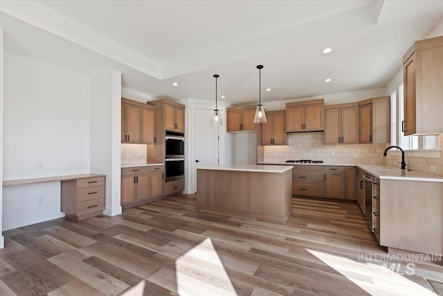 kitchen featuring a center island, sink, hanging light fixtures, and light wood-type flooring