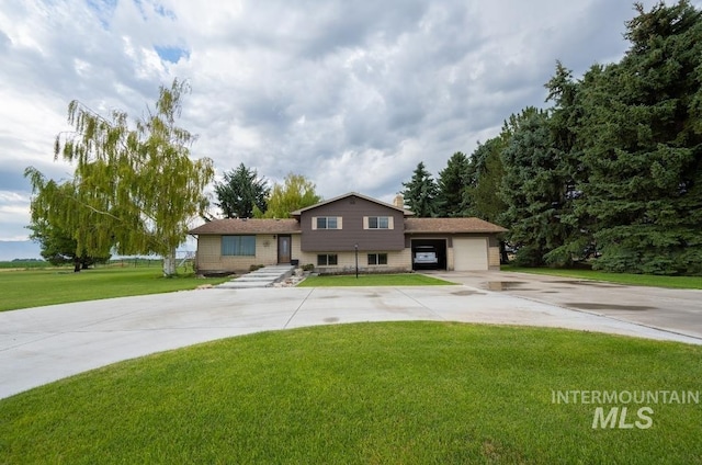 split level home with an attached garage, concrete driveway, and a front yard