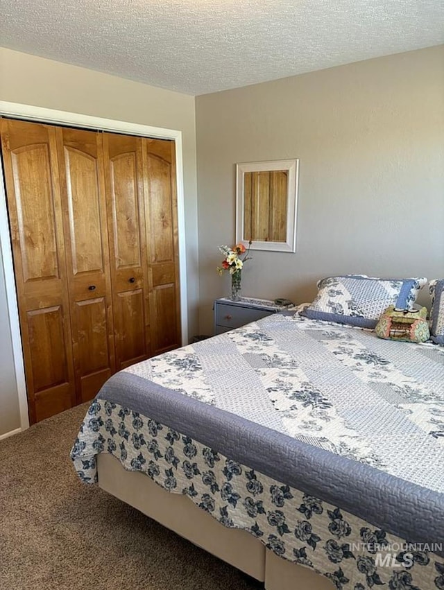 carpeted bedroom featuring a textured ceiling and a closet