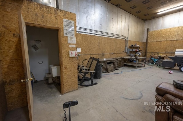 miscellaneous room featuring concrete flooring and a towering ceiling