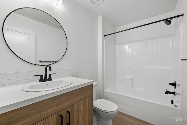 full bathroom with toilet, bathtub / shower combination, decorative backsplash, wood-type flooring, and vanity