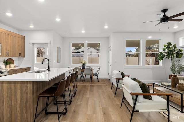 kitchen with sink, a breakfast bar area, light wood-type flooring, and plenty of natural light