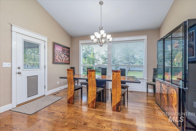 dining area featuring an inviting chandelier, baseboards, wood finished floors, and vaulted ceiling