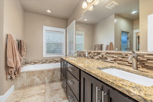 full bathroom with double vanity, decorative backsplash, a sink, and a bath
