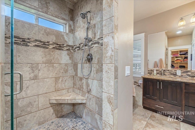 full bathroom with a spacious closet, a shower stall, and vanity