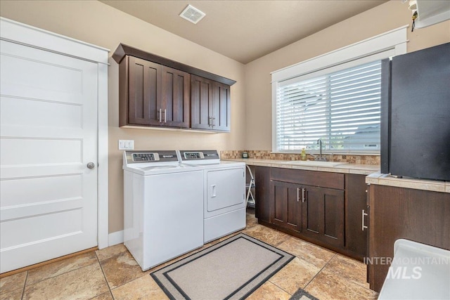 washroom featuring cabinet space, visible vents, washer and clothes dryer, and a sink