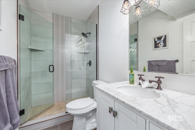 full bath with vanity, a shower stall, and toilet