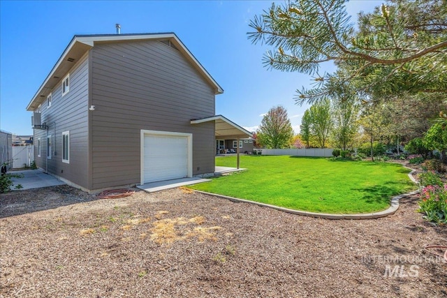 view of side of home with a lawn, a garage, and fence
