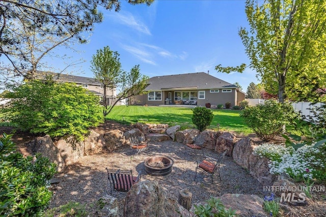 rear view of house featuring a lawn, a fire pit, and fence private yard