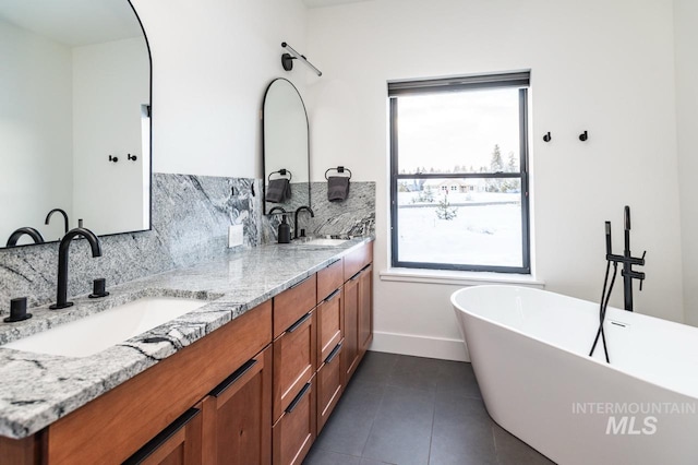 1047 Kaitlyn Loop, Mccall, ID 83638 - bathroom featuring tasteful backsplash, double vanity, a freestanding bath, baseboards, and tile patterned flooring