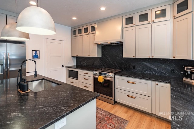 1047 Kaitlyn Loop, Mccall, ID 83638 - kitchen featuring stainless steel appliances, custom exhaust hood, a sink, light wood-style flooring, and backsplash
