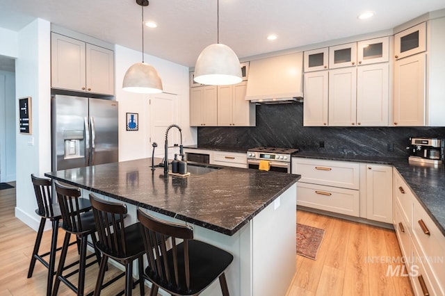 1047 Kaitlyn Loop, Mccall, ID 83638 - kitchen featuring appliances with stainless steel finishes, a sink, custom range hood, light wood-style floors, and backsplash