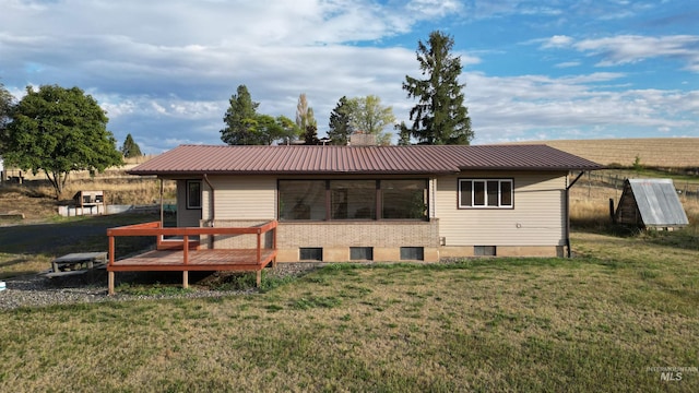 back of house with metal roof, brick siding, and a yard