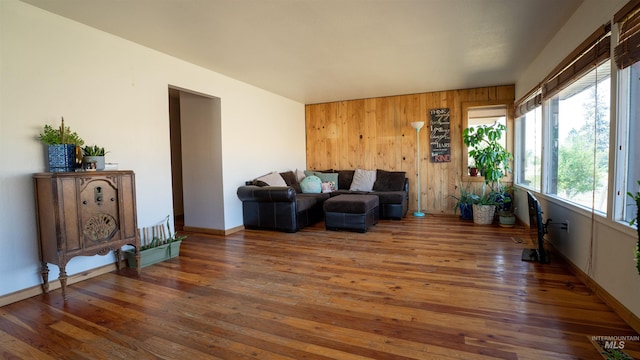 living area with wooden walls, wood-type flooring, and baseboards