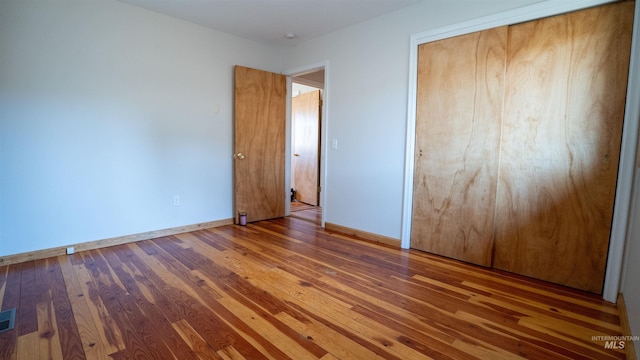 unfurnished bedroom with a closet, baseboards, and hardwood / wood-style flooring