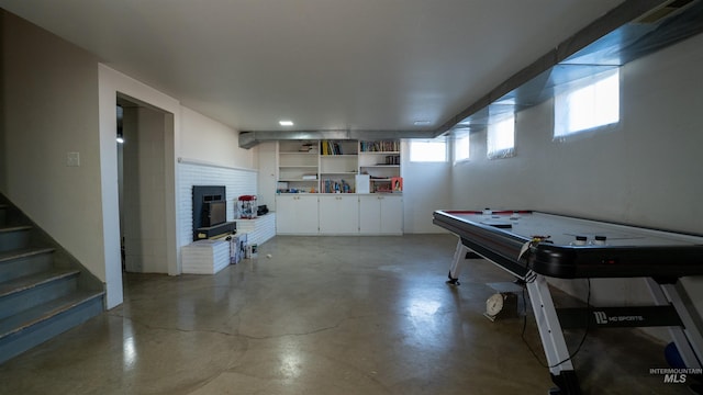 game room with a brick fireplace, visible vents, and concrete floors