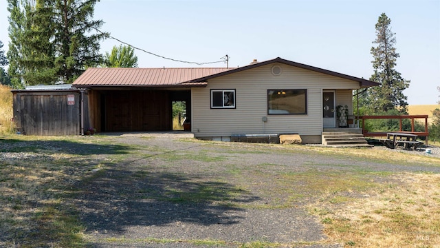 back of property featuring metal roof, driveway, and a carport