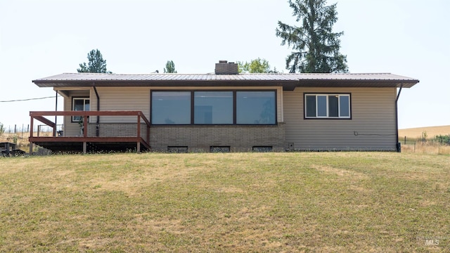 rear view of house featuring metal roof, brick siding, a yard, and a chimney